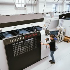 Photo of a man operating a 3D printer at America Makes. Photo credit: NIST