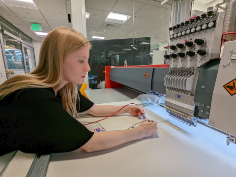 Image of a woman using soldering a chip to fabric.