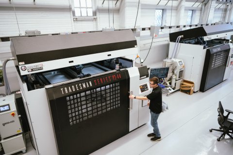 Photo of a man operating a 3D printer at America Makes. Photo credit: NIST