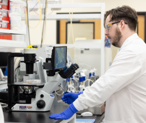 Photo of Tim Kelley working in a lab wearing safety glasses and a white lab coat