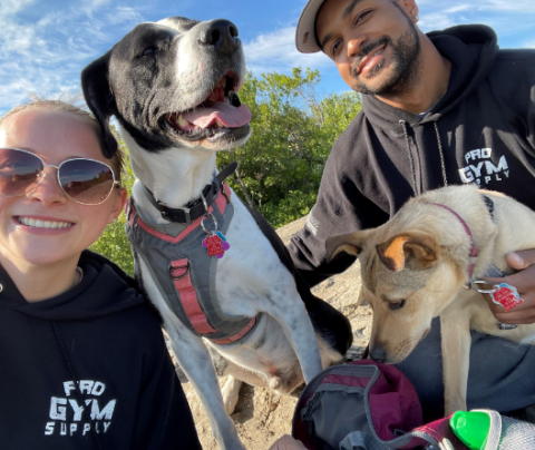 Photo of Gabrielle Mourousas, her two dogs, and partner sitting outside