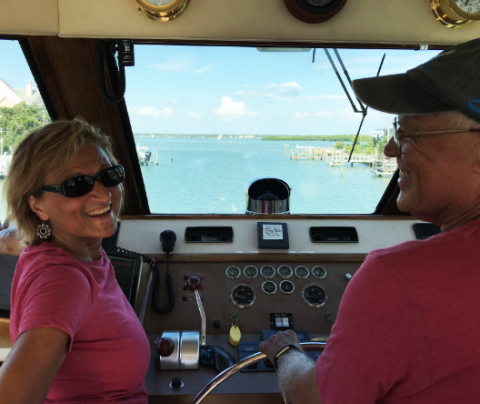 Photo of Kathie Leonard and her husband steering a boat.