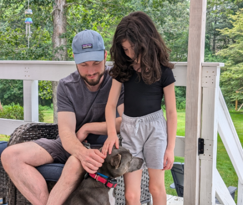 Photo of Jim Owens with his daughter sitting outside with their dog