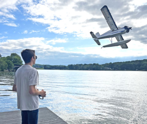 Photo of Sam flying a radio controlled airplane at a lake.