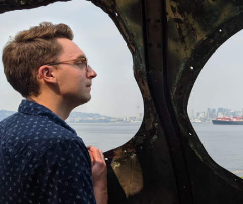 Photo of Jackson Rambough looking out over a vista with a city and boats in the background